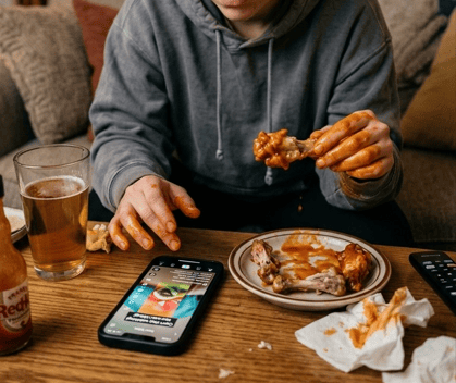 Mujer comiendo alitas ensuciando la pantalla